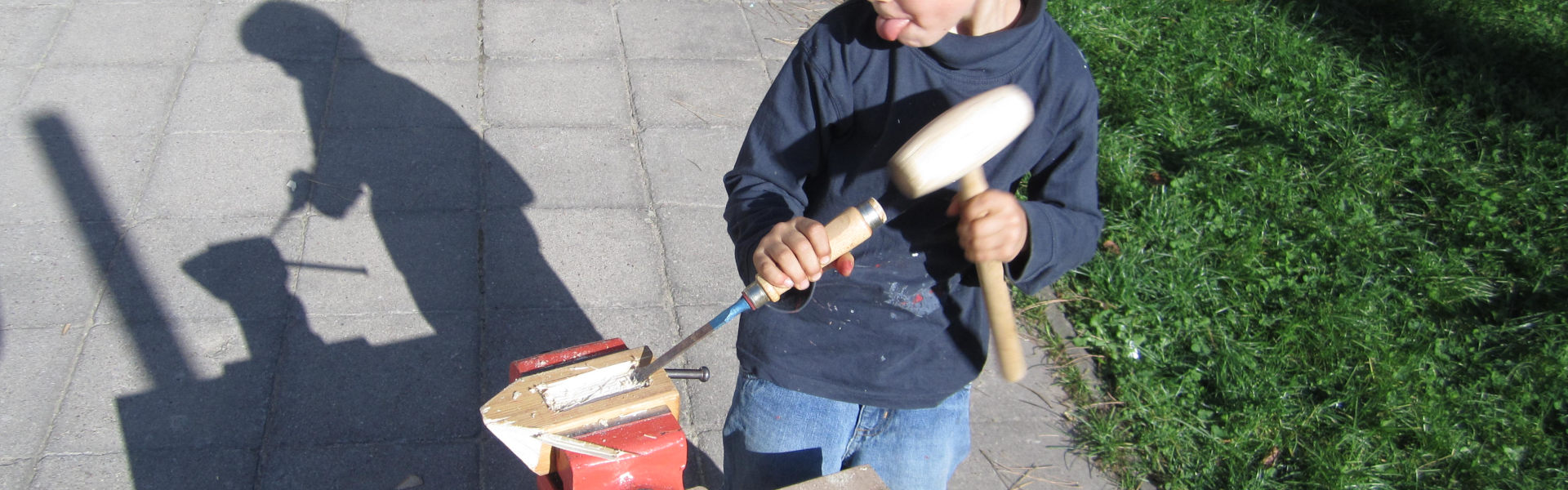 Banner Titelbild Bauideen – Kind beitelt ein Boot aus einem Stück Holz